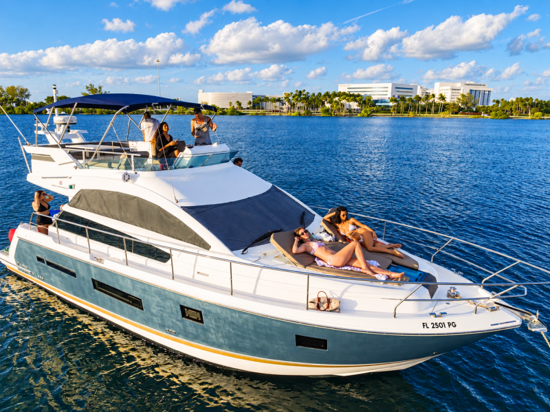 People relaxing on a luxury yacht in a sunny, blue-skied harbor.
