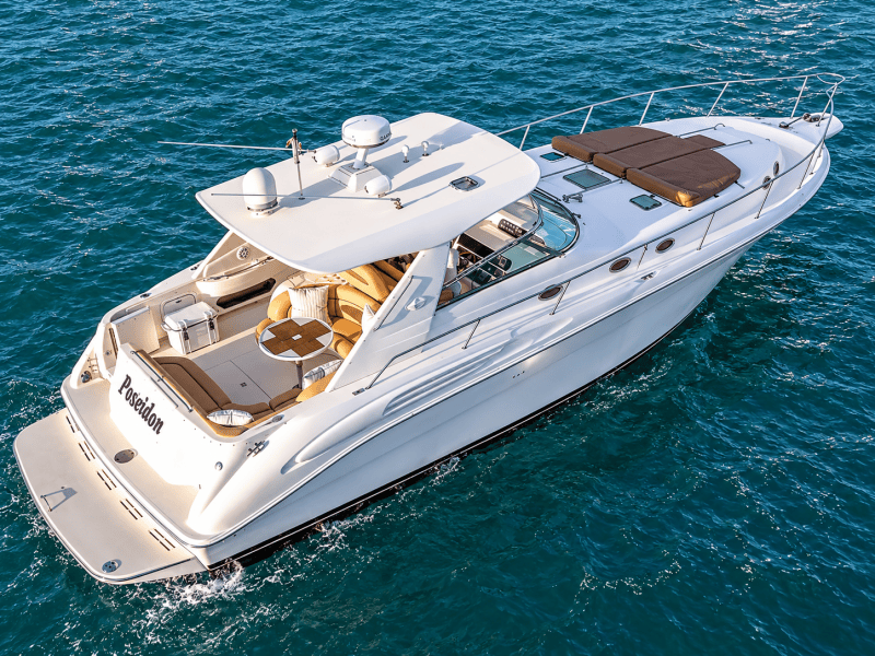 Luxury yacht named Poseidon cruising on the ocean with clear blue water.