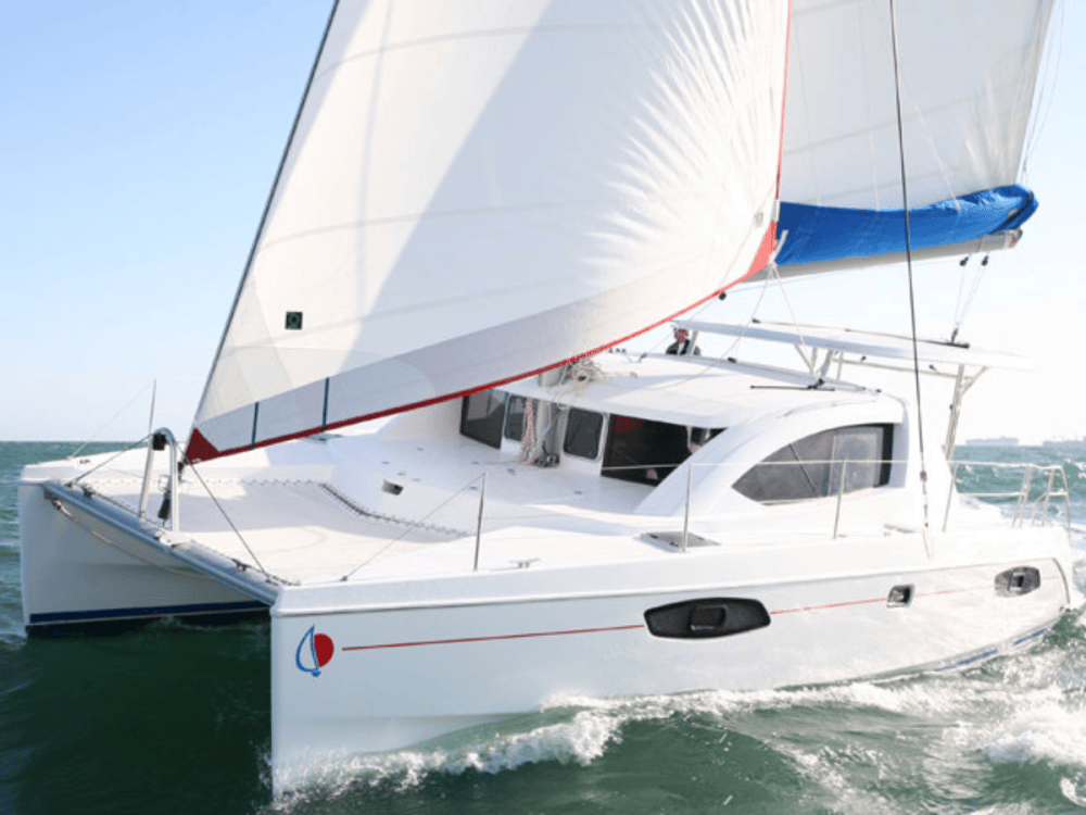 White catamaran sailing on a sunny day with full sails.