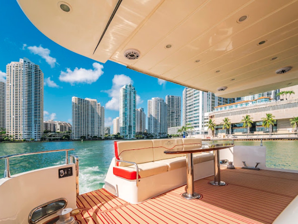 View of a city skyline from a boat deck with seating and a table.