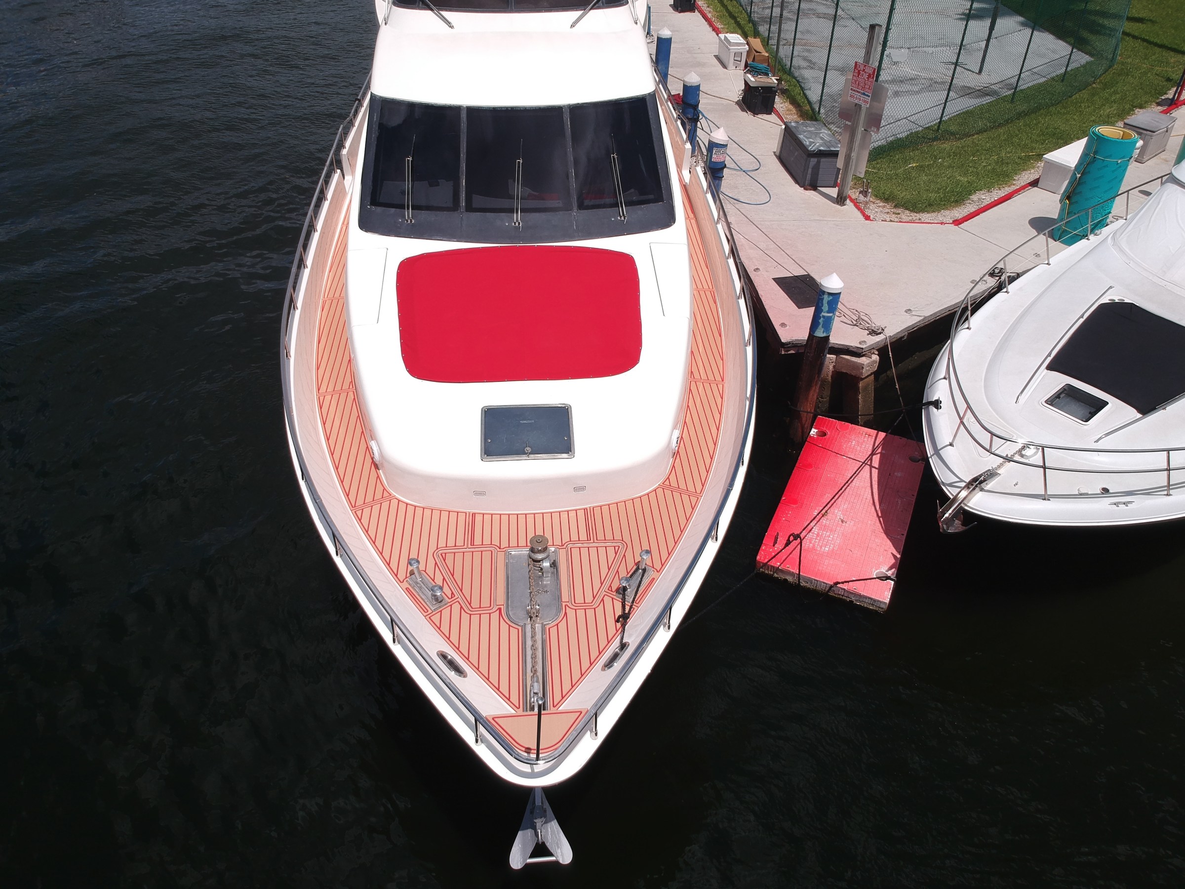 Aerial view of a red and white boat docked beside another boat on a dark water surface.