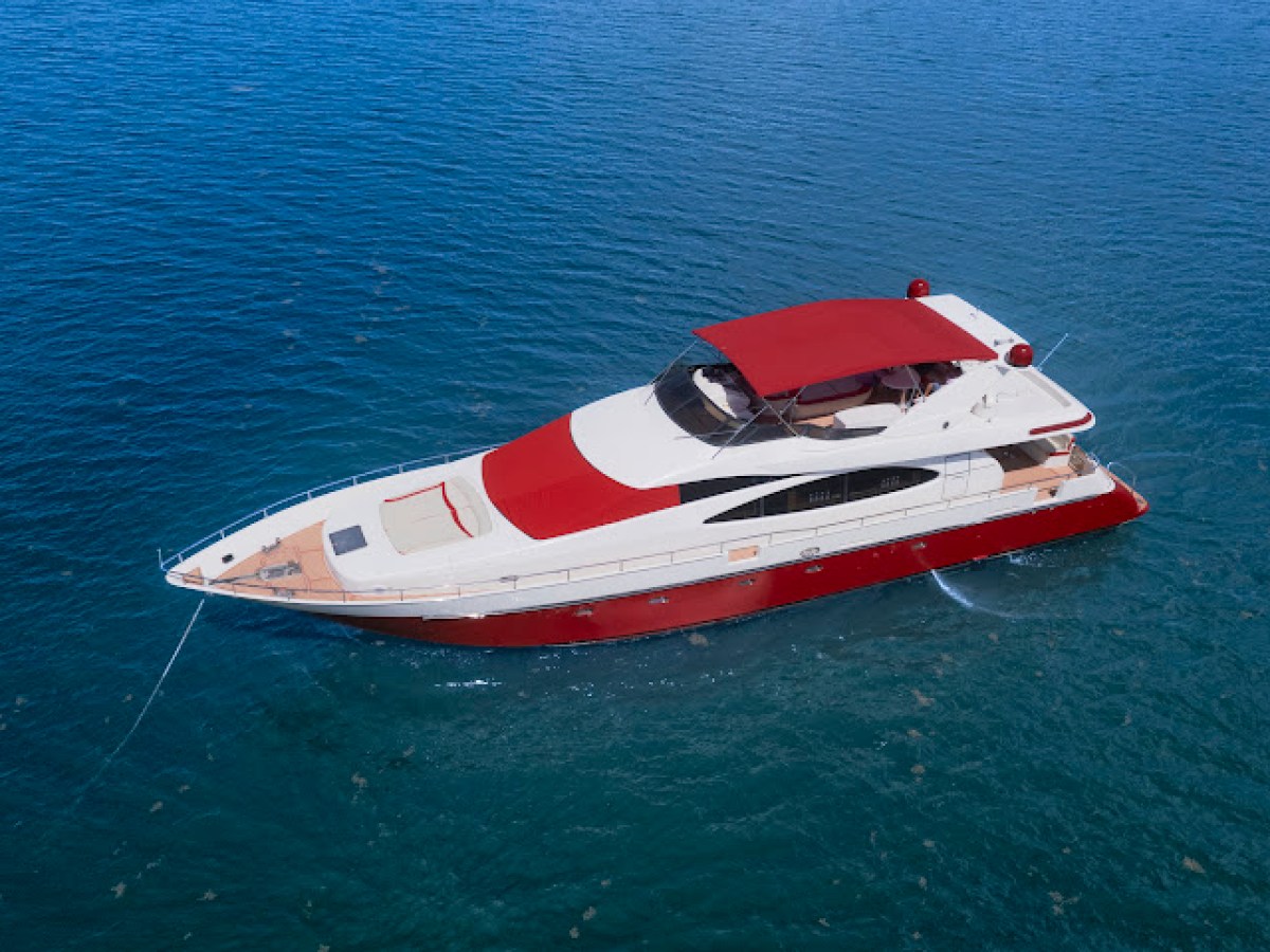 Luxury yacht with red accents on blue water, viewed from above.