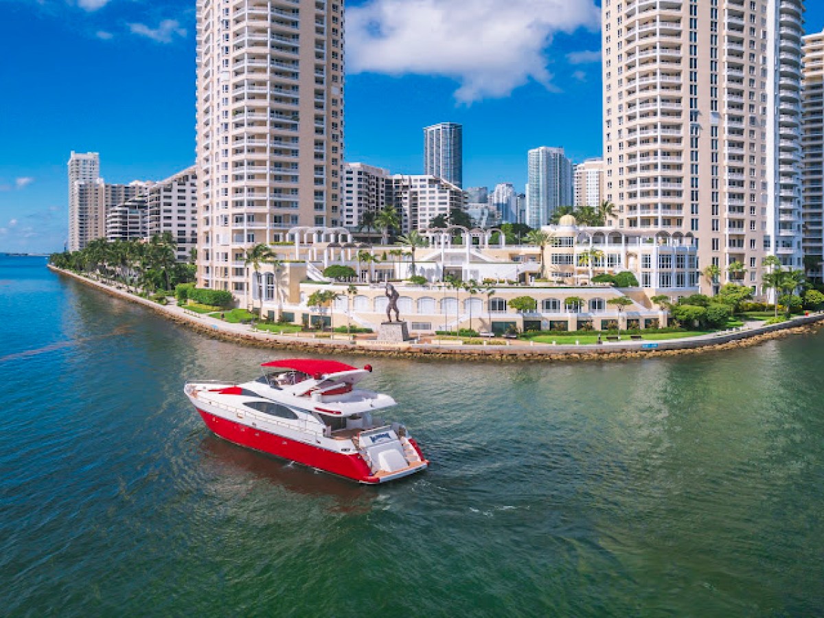Red and white yacht near high-rise buildings by waterfront.