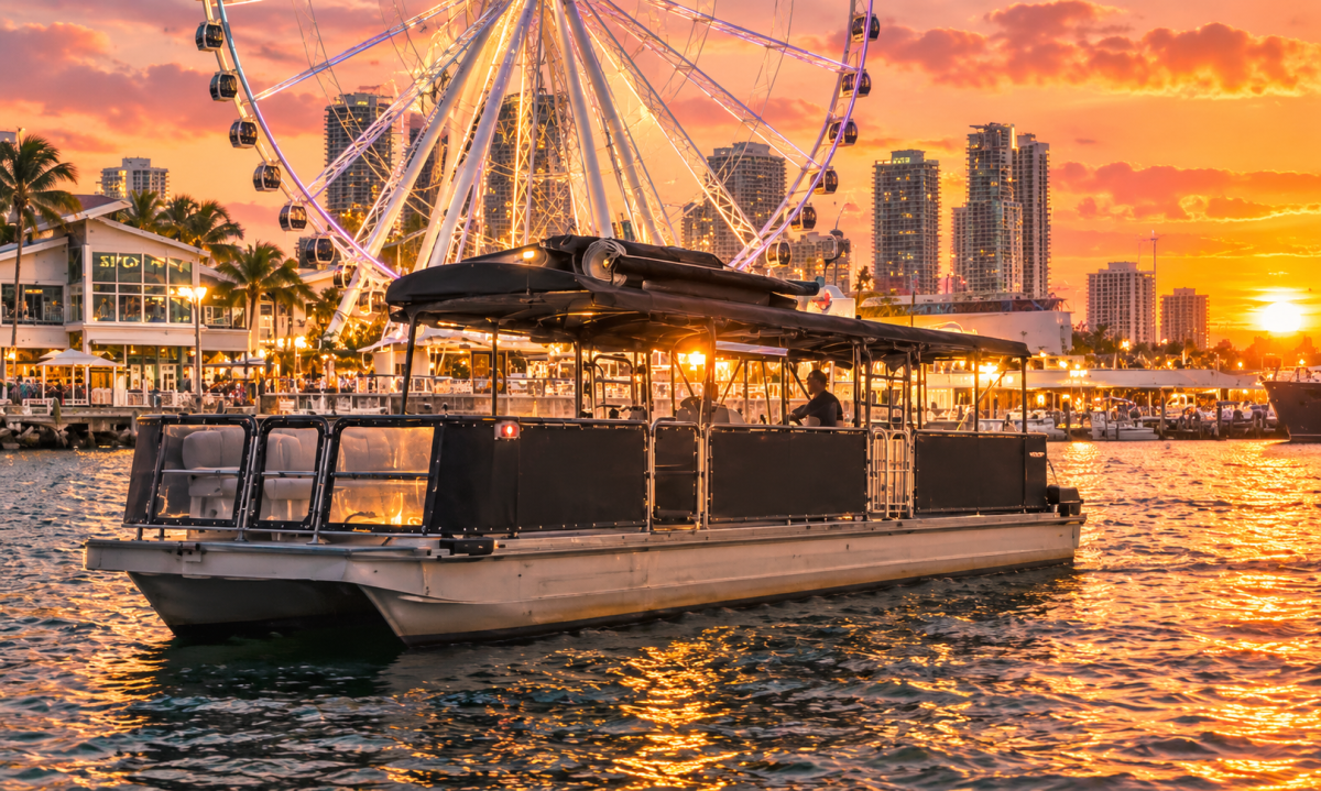 Pontoon boat on water at sunset, Ferris wheel and city skyline in background.