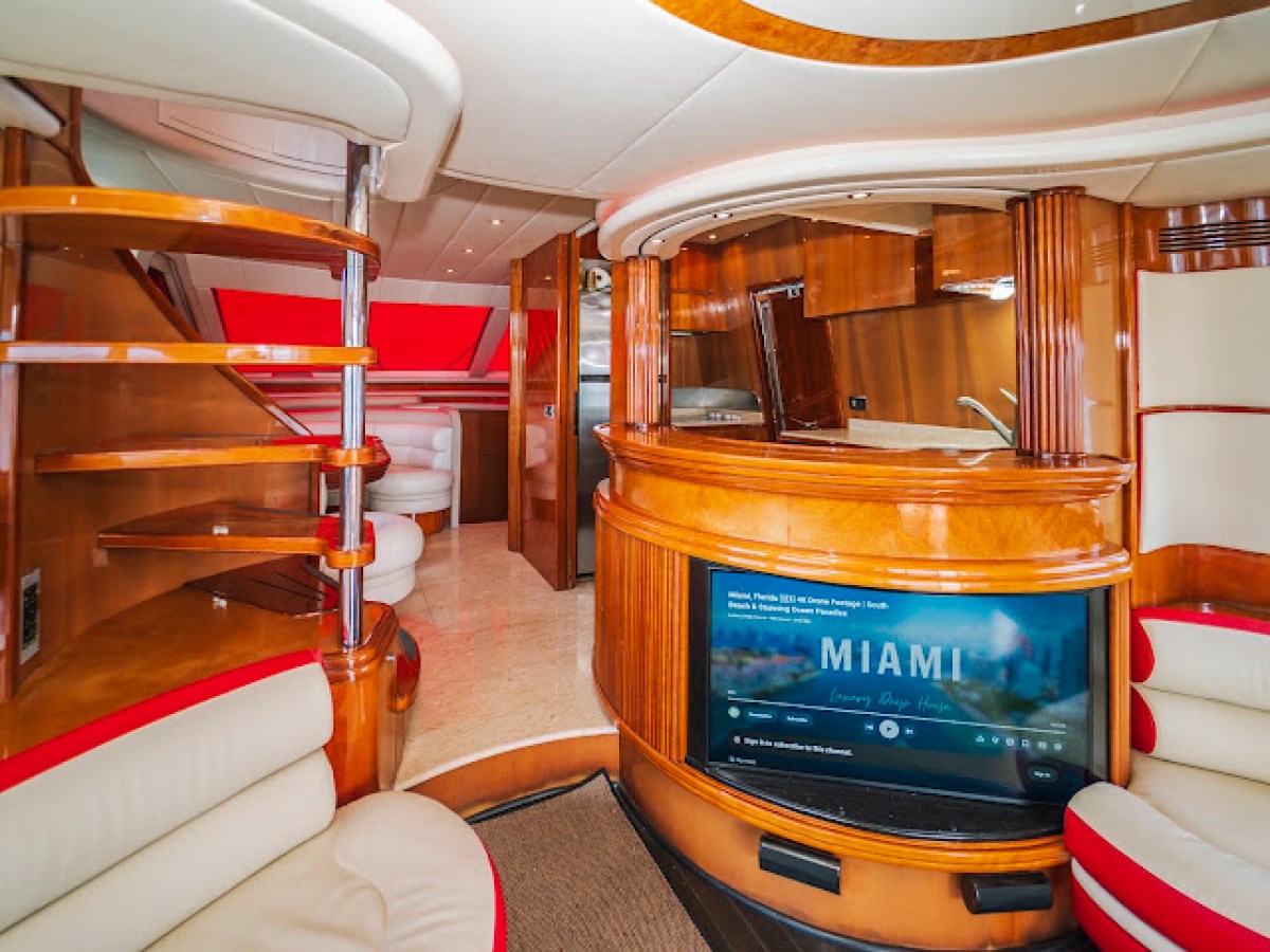 Luxurious yacht interior with wood paneling, curved stairs, and a flat-screen TV.