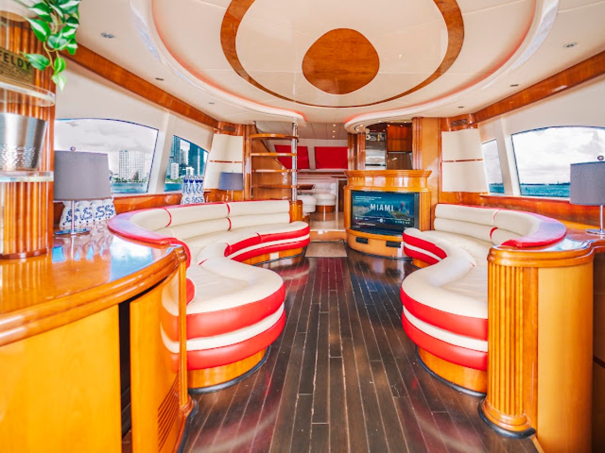 Luxurious yacht interior with curved red and white seating, wooden accents, and large windows.