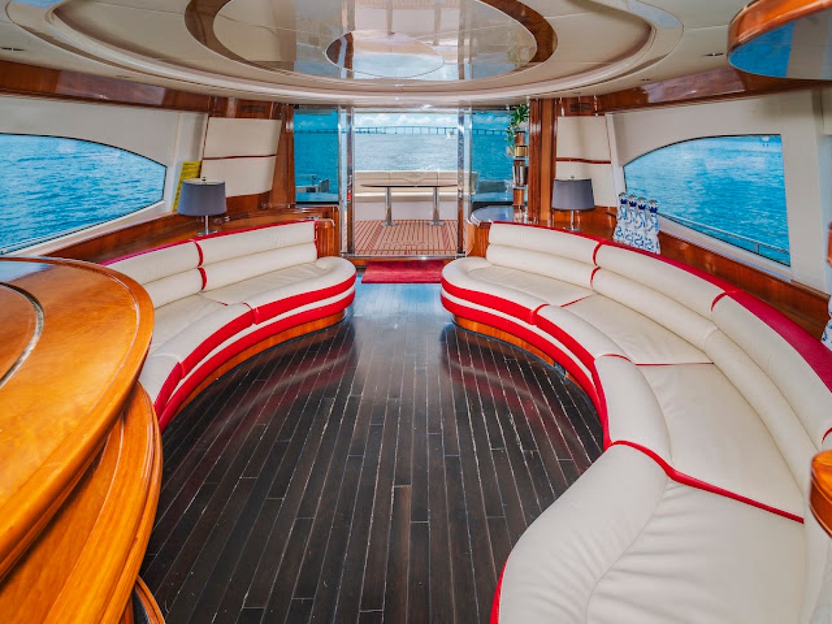 Luxurious yacht interior with curved white sofas and wooden accents, overlooking the ocean.