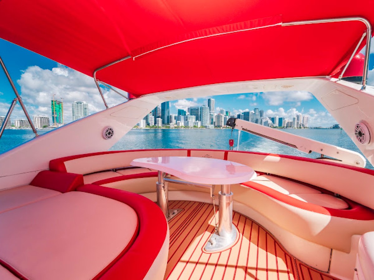 Boat interior with red canopy, waterfront city skyline view.