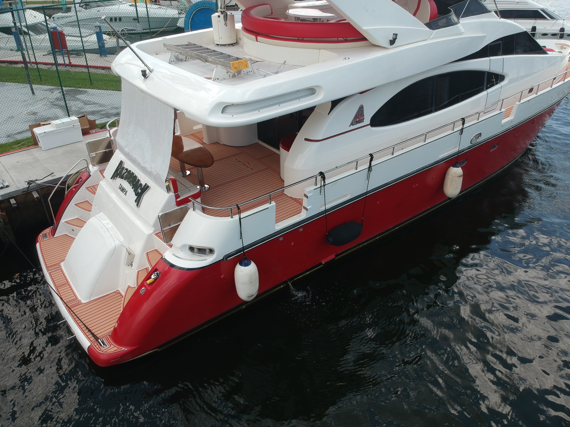 Red and white luxury yacht docked at a marina.